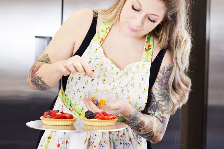 Natalie Schultz, founder and head pastry chef, holding a plate of decorated desserts
